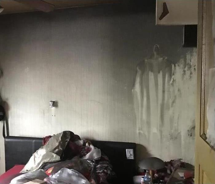 Bedroom damaged by fire. Bedroom walls, bed and personal items covered with soot.
